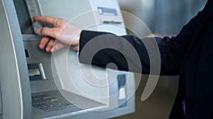 Client entering pin code on ATM to receive money, banking services, withdrawing