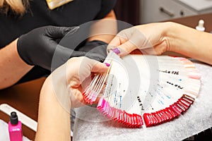 The client in the salon of manicure chooses the color of nail Polish