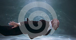 Client service professional. Young coach businessman in black corporate office suit swims underwater to work slow motion