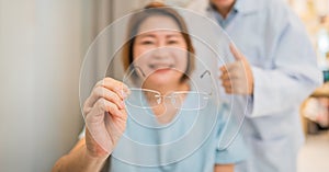 Client testing her new eyeglasses with optometrist in optical store