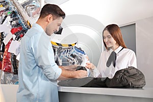 Client and worker with jacket at dry-cleaner`s
