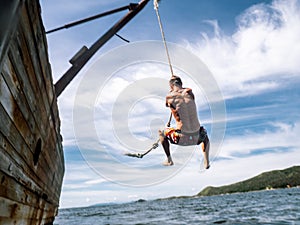 Cliff jumping: A young guy in shorts jumps into seawater from the side of an old ship.
