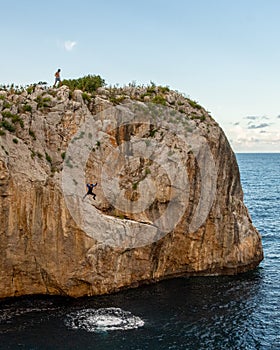 Cliff next to a sea with people jumping in it