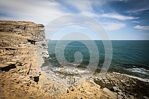 Cliff on spring time with the deep blue sea and sky with clouds