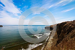 Cliff on spring time with the deep blue sea and sky with clouds