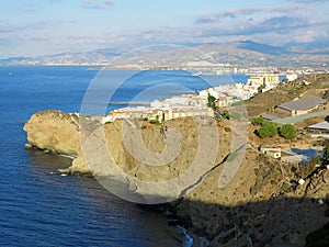 Cliff view of the Mediterranean sea, town of Torrenueva and mountains in the distance photo