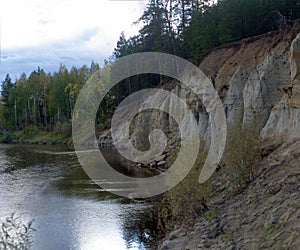 The cliff in the woods North of the river in Yakutia, Kempendyay with spruce forest.