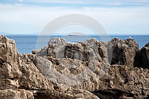 Cliffs against the background of the blue Atlantic Ocean and a ship in a blurry focus.