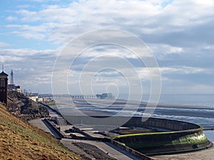 Cliffs area on the south promenade in Blackpool with the beach at low tide with the pier and tower in the distance