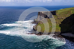 Cliffs of Moher at Alantic Ocean in Western Ireland with waves battering against the rocks photo