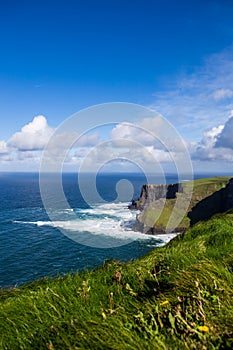 Cliffs of Moher at Alantic Ocean in Western Ireland with waves battering against the rocks photo