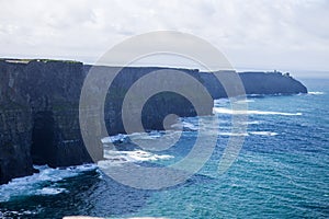 Cliffs of Moher at Alantic Ocean in Western Ireland with waves battering against the rocks photo