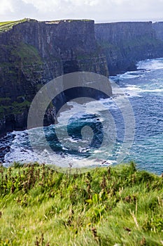 Cliffs of Moher at Alantic Ocean in Western Ireland with waves battering against the rocks photo