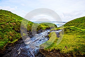 Cliffs of Moher with small creek at Alantic Ocean in Western Ireland with waves battering against the rocks