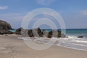 Cliffs of solidified volcanic lava on Virgin Beach in Bali. Black rocks with rough surface.