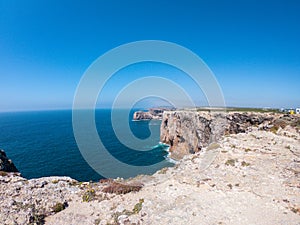 Cliffs on west coast of Atlantic Ocean in Sagres, Algarve, Portugal. Horizon over water against claer blue sky
