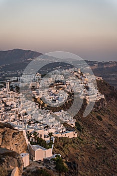 Cliffside homes in Santorini at sunset in summer