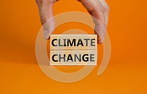 Climate change symbol. Wooden blocks with words `Climate change` on beautiful orange background. Businessman hand. Business,