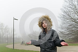 Climate change. Waiting for snow. Portrait of a teenage girl in a foggy park