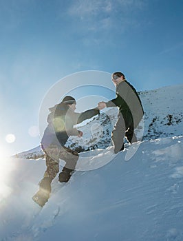 Climber assists another climber on the slope of snowy mountains