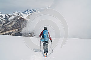 Climber with backpack and trekking poles descending Mera peak high slopes at cca 6000m enjoying legendary Mount Everest, Nuptse,