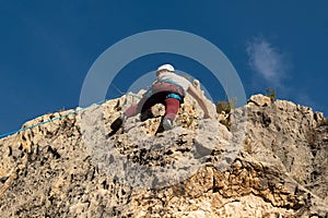 Climber boy reaches the end of the climbing route next to the reunion