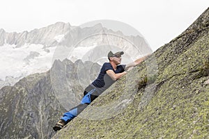 Climber climbs on a sloping rock wall in the Swiss mountains