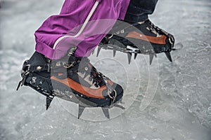 Climber on a frozen waterfall. Crampons close-up on his feet ice climber