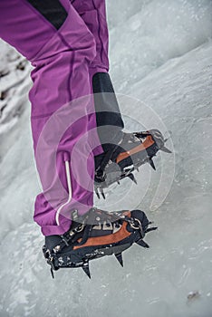 Climber on a frozen waterfall. Crampons close-up on his feet ice climber