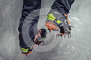 Climber on a frozen waterfall. Crampons close-up on his feet ice climber