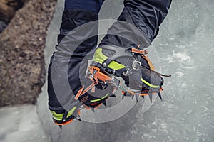 Climber on a frozen waterfall. Crampons close-up on his feet ice climber