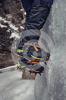 Climber on a frozen waterfall. Crampons close-up on his feet ice climber