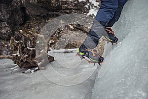 Climber on a frozen waterfall. Crampons close-up on his feet ice climber