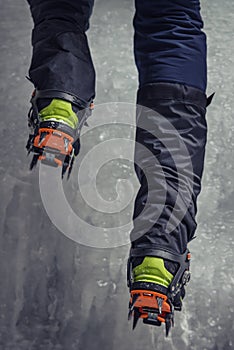 Climber on a frozen waterfall. Crampons close-up on his feet ice climber