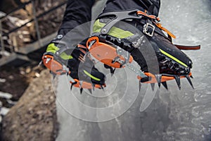 Climber on a frozen waterfall. Crampons close-up on his feet ice climber