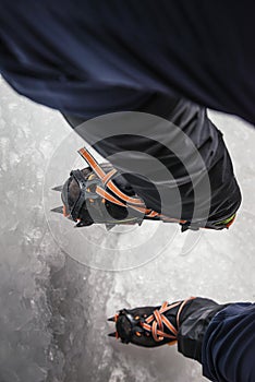 Climber on a frozen waterfall. Crampons close-up on his feet ice climber