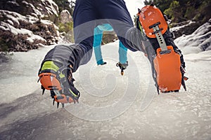 Climber on a frozen waterfall. Crampons close-up on his feet ice climber