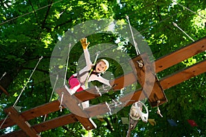 Climber little girl on training. Toddler climbing in a rope playground structure. Cute school little girl enjoying a