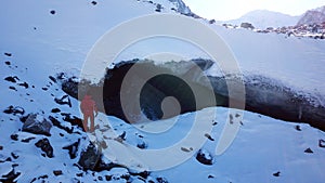 A climber looks at the entrance to an ice cave.