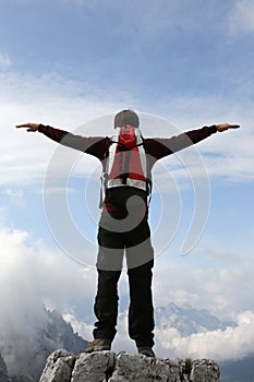 Climber on a mountain top stretching his arms like flying