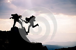 Climber reaches out to his partner by helping each other.leading climbers;Team work, life goals and self improvement concept