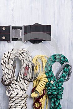 Climber`s belt with different ropes and carbines for insurance lie on a light background