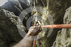 Climber`s hand clicks the rope in carbine