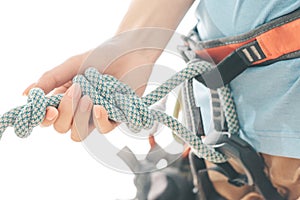 Climber in safety harness holding rope knot eight, close-up.