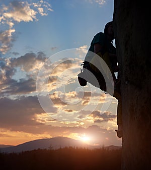 Climber silhouette climbing, challenging rocky route. Sunset in mountains. Extreme, activity, rock climbing. Copy space