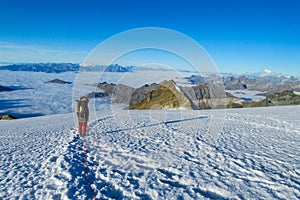 Climber on snow mountain ridge above the clouds