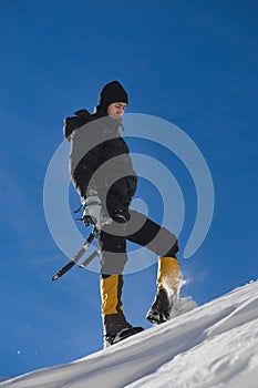 Climber walk on the mountain through snow blown away by the strong wind.