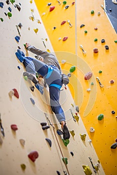 Climber on wall.Young man practicing rock climbing on a rock wall indoors