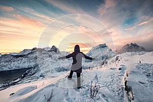 Climber woman standing on snowy peak and mountain range view in the morning on mount Segla at Senja island