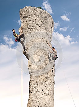 Climbers in action, young woman and man climbing.